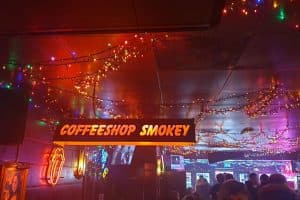 שלט COFFEESHOP SMOKEY כתום תלוי מהתקרה בין שרשראות אורות וניאון לשון הרולינג סטונס