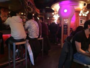 לקוחות על שרפרפים ליד הבר בדאמפקרינג, בתאורה סגולה ותקרה מגולפת