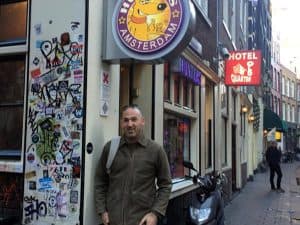 סניף האנטר בפינת סמטה: שלט עגול Hunters Amsterdam, קיר מכוסה מדבקות ואיש בכניסה
