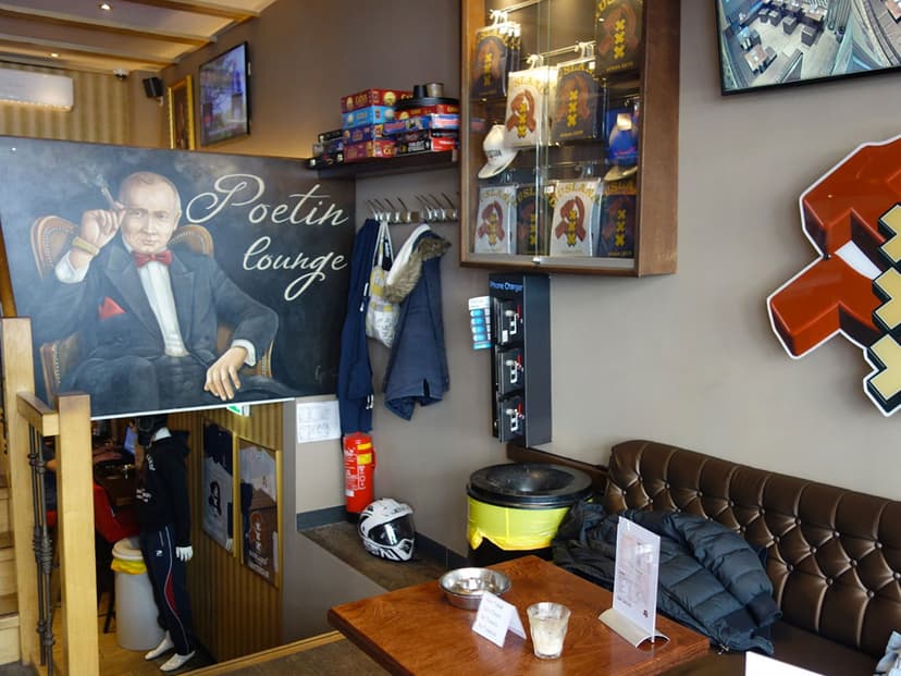 ציור Poetin Lounge וספת עור חומה בטרקלין של רוסלנד, לצד ויטרינת מזכרות ועמדת טעינה לטלפונים